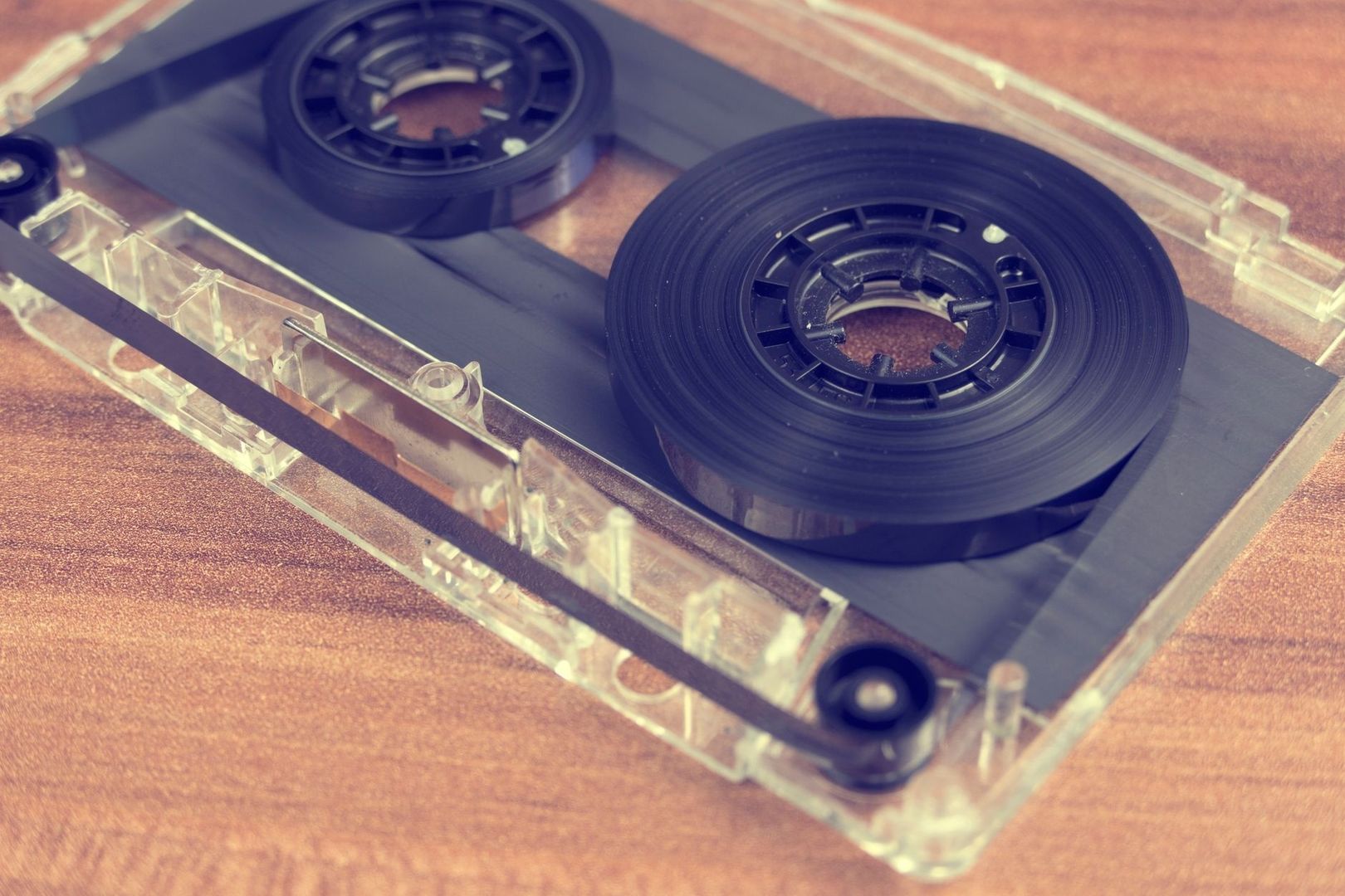 Open cassette tape with two black reels and exposed magnetic tape