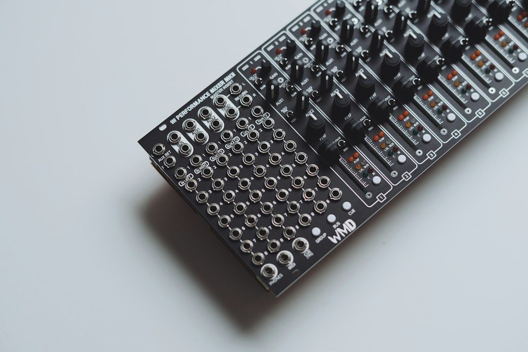 Close-up of a black audio mixer with knobs, jacks, and level meters