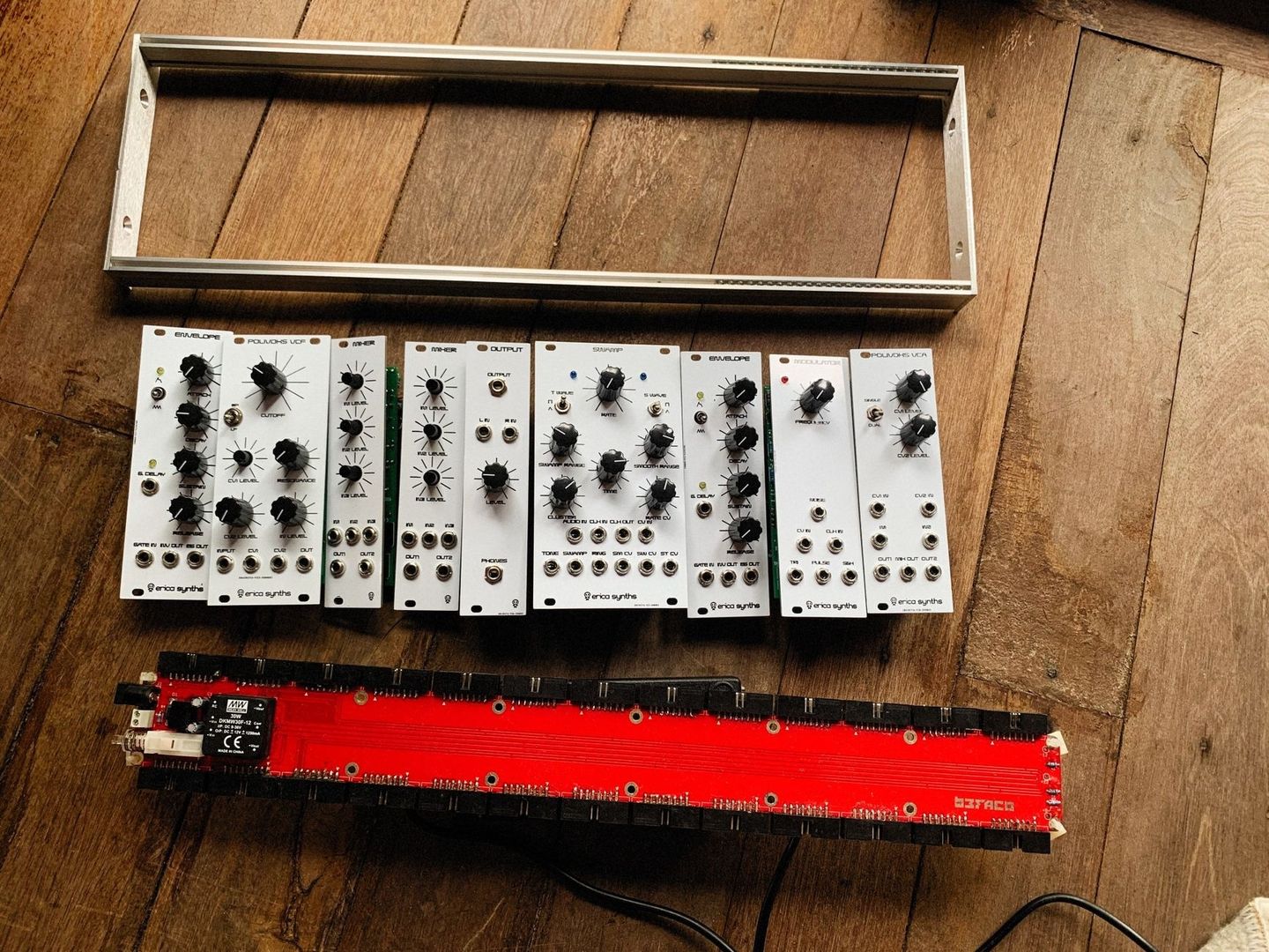 Modular synthesizer modules and red Eurorack case on a wooden floor
